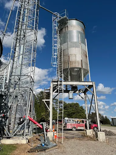 Grain bin with access ladder under a blue sky